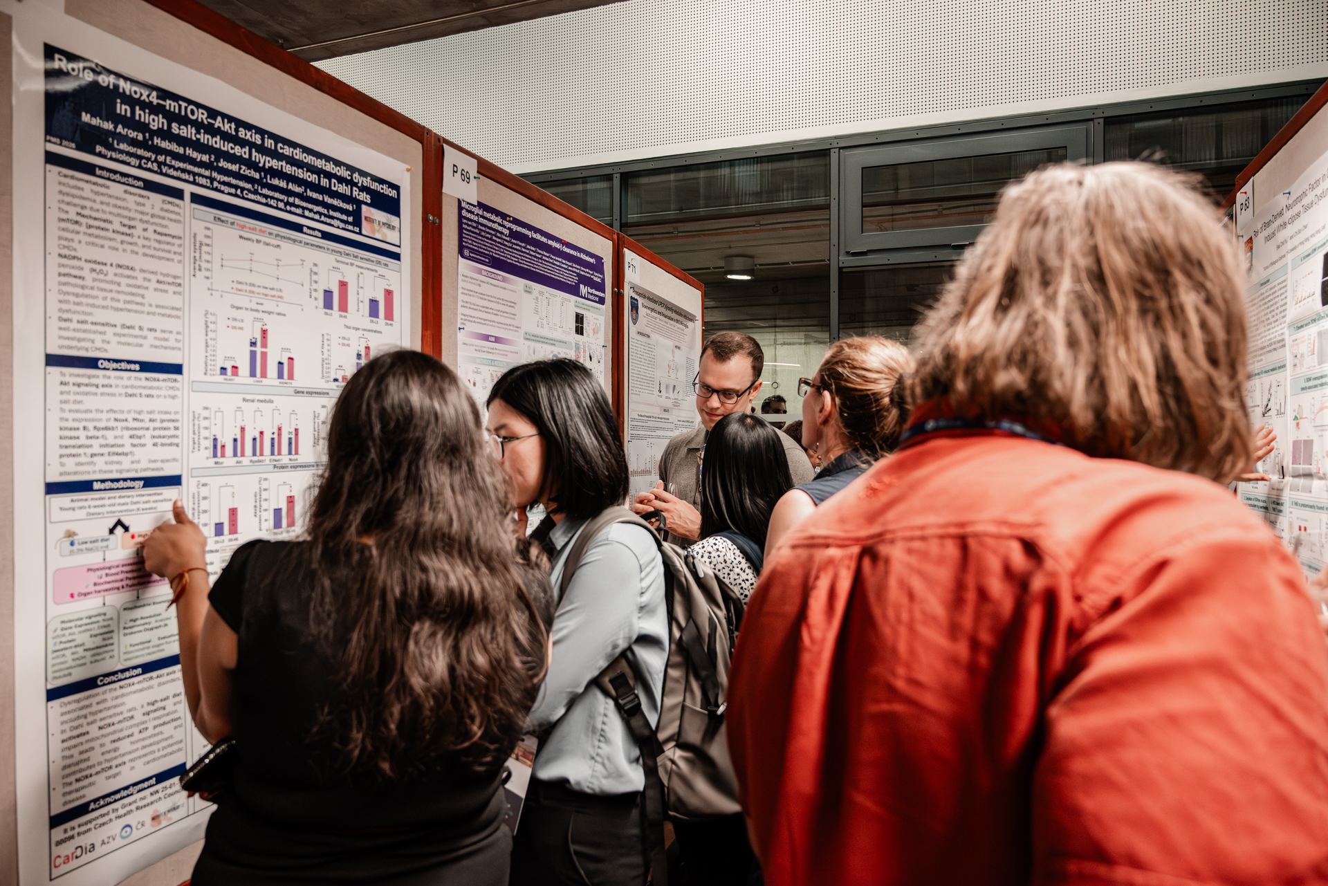 Researchers gathered around conference posters, talking through the work.